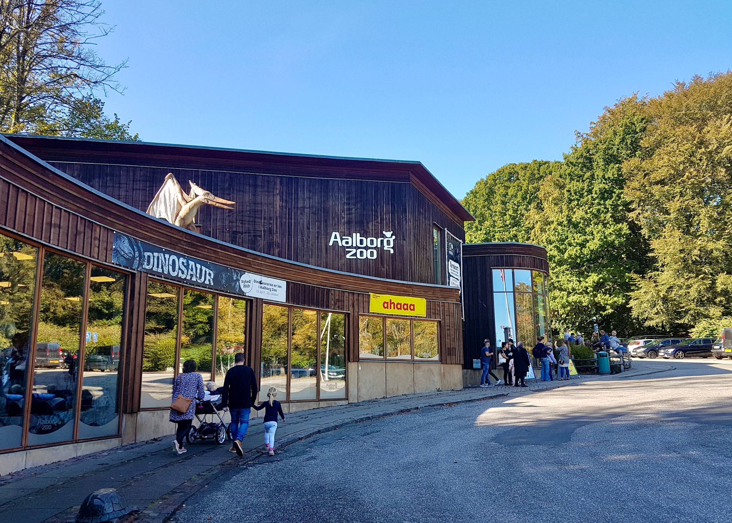 Hölzernes Eingangsgebäude des Zoos, auf dem Dach ein Flugsaurier