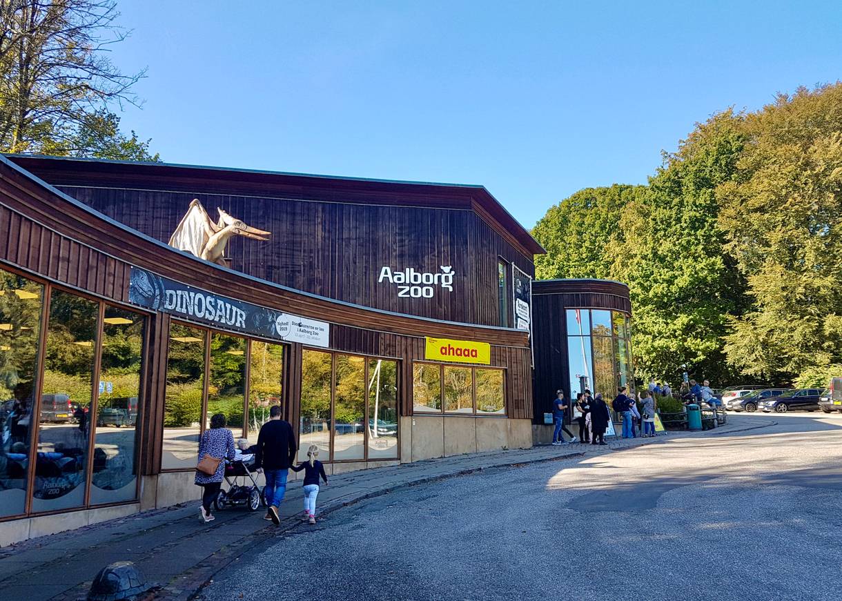 Hölzernes Eingangsgebäude des Zoos, auf dem Dach ein Flugsaurier