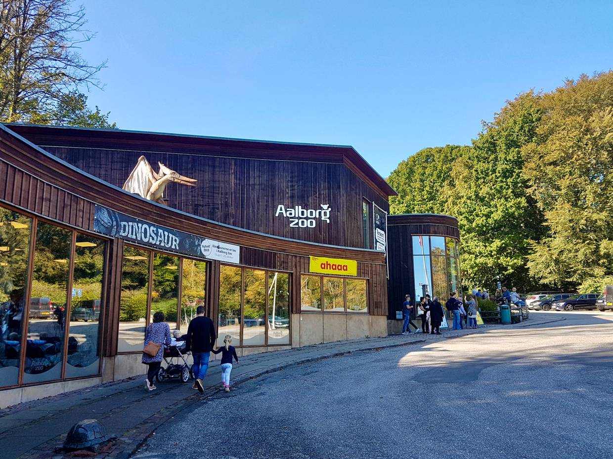 Hölzernes Eingangsgebäude des Zoos, auf dem Dach ein Flugsaurier