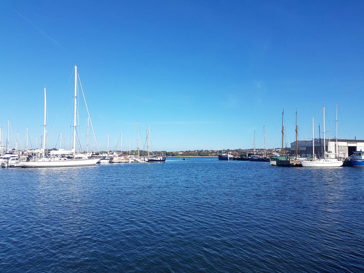 Aussicht auf den Jachthafen, links große Segeljachten, rechts eine Werft