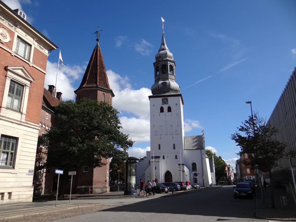 Straßenzug mit weißer Kirche am Ende, davor ein roter Backsteinturm