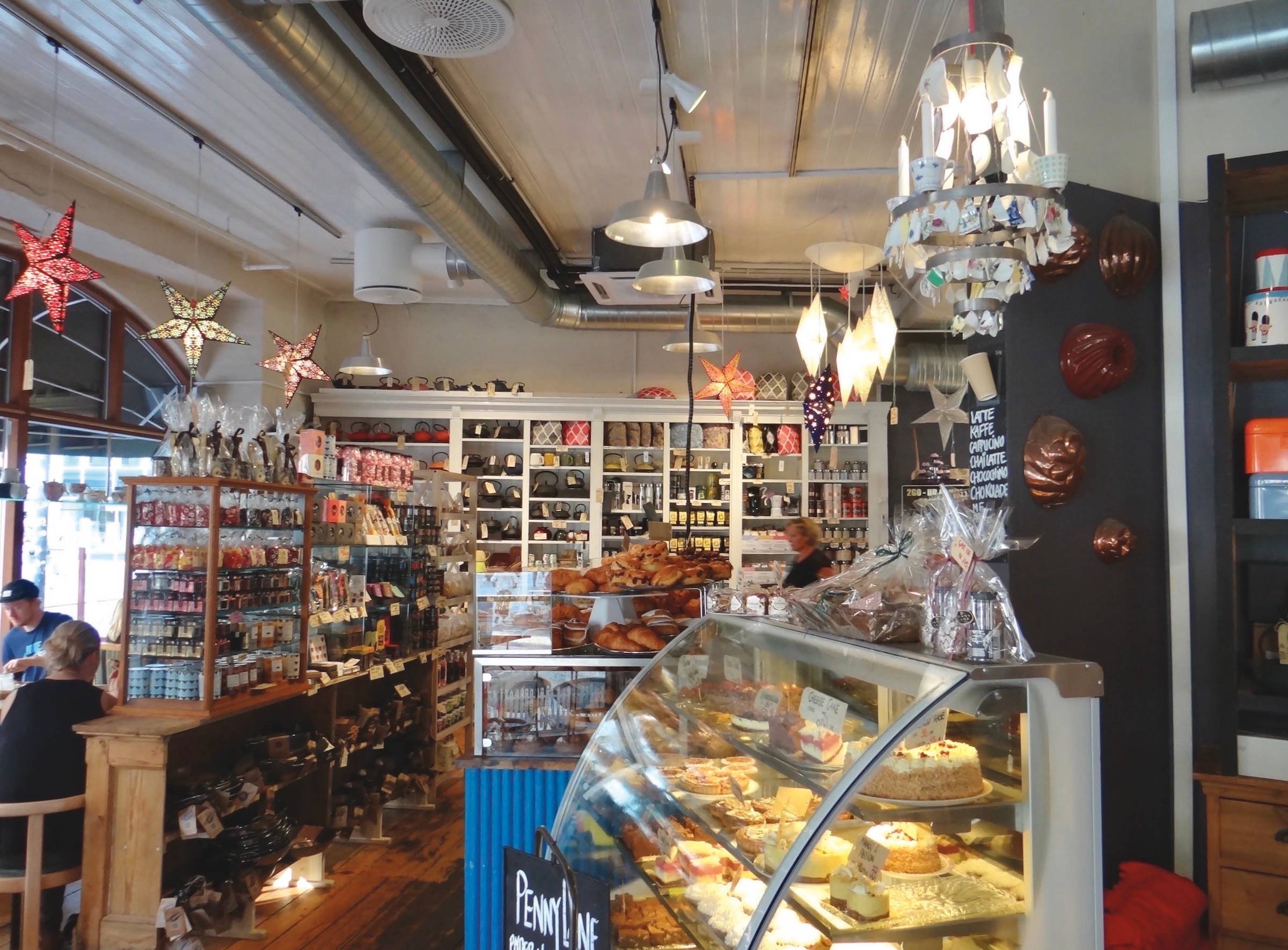 Tresen und einige Tisch in einem Café mit sehr dicht gepackten Auslagen