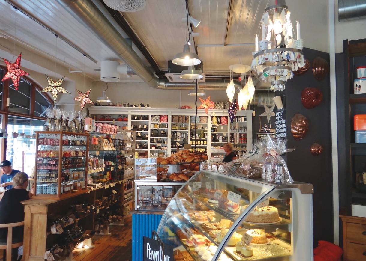 Tresen und einige Tisch in einem Café mit sehr dicht gepackten Auslagen