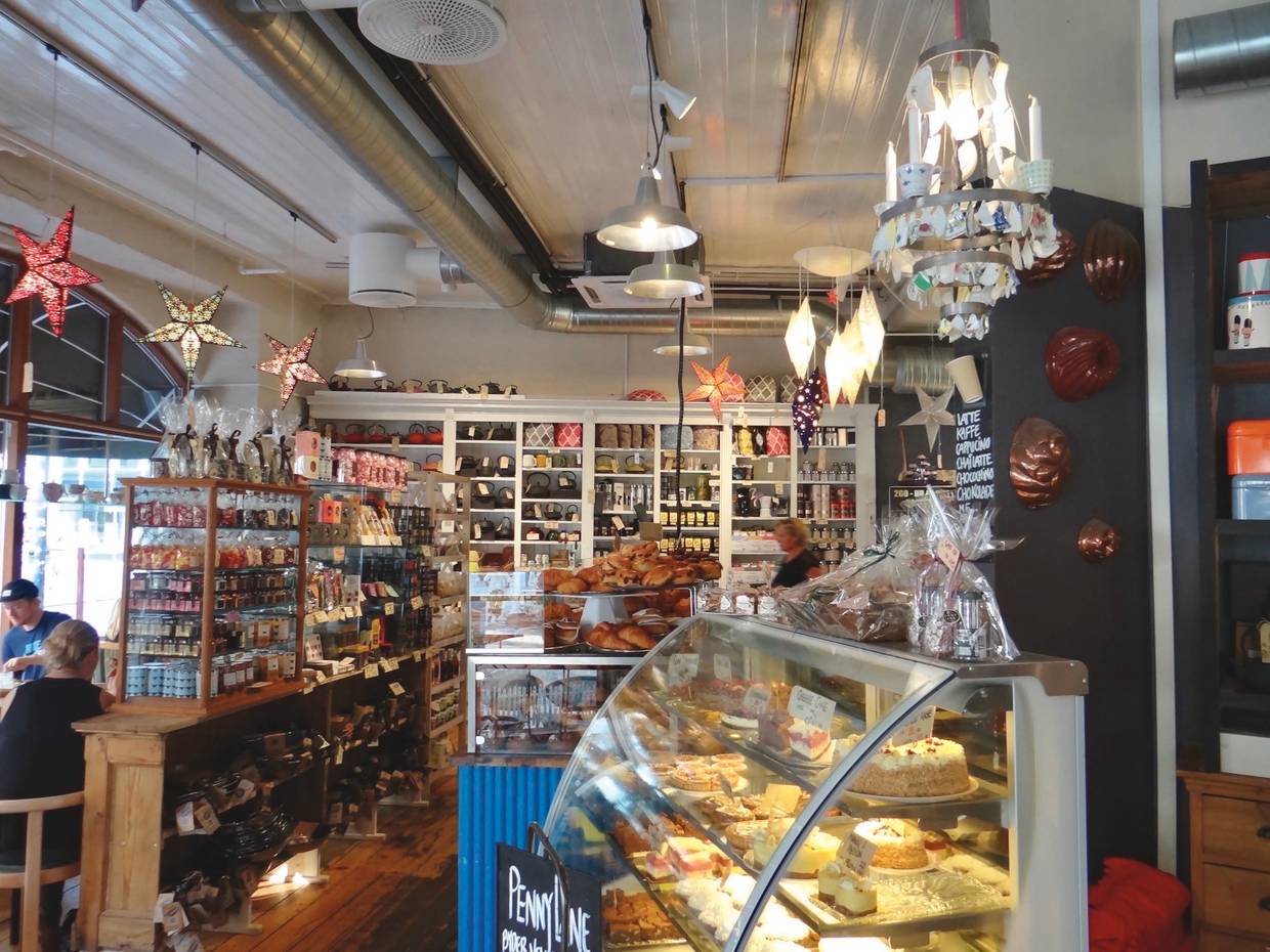 Tresen und einige Tisch in einem Café mit sehr dicht gepackten Auslagen
