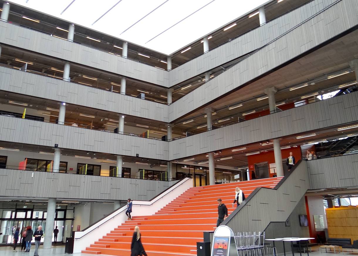 Eingangshalle mit offenen Balkonen über vier Etagen und einer breiten, roten Treppe