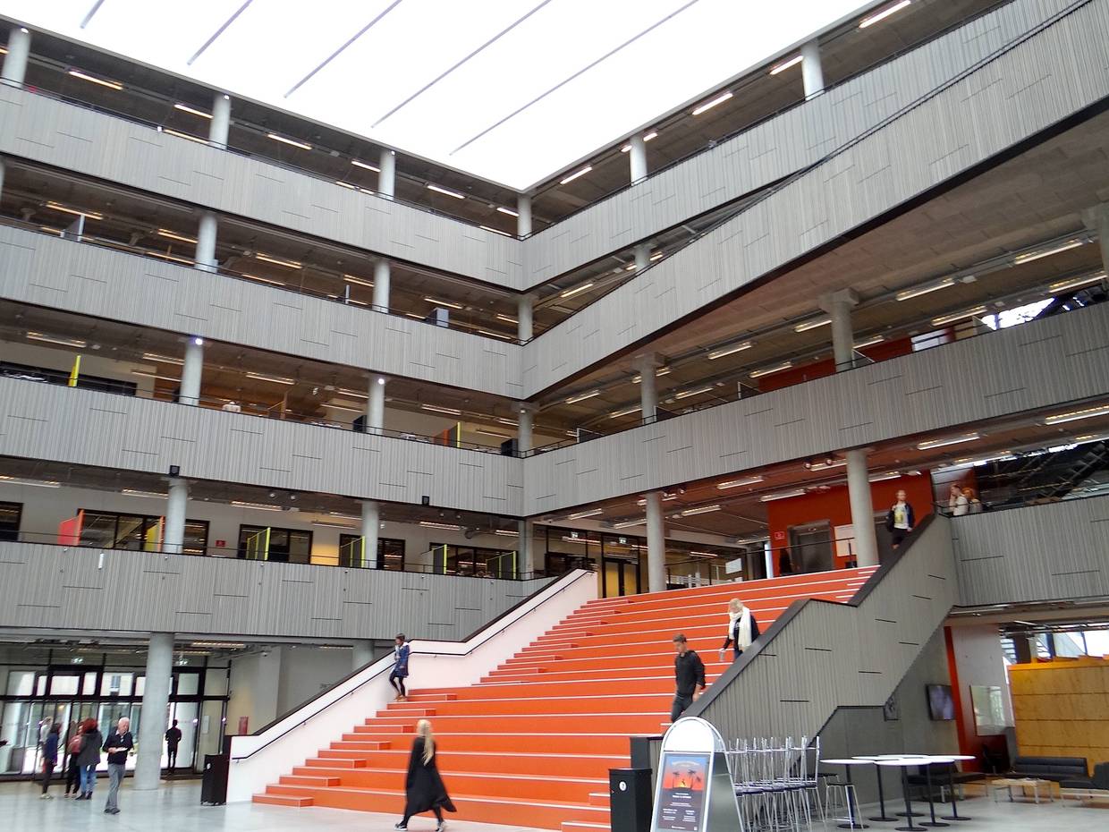 Eingangshalle mit offenen Balkonen über vier Etagen und einer breiten, roten Treppe