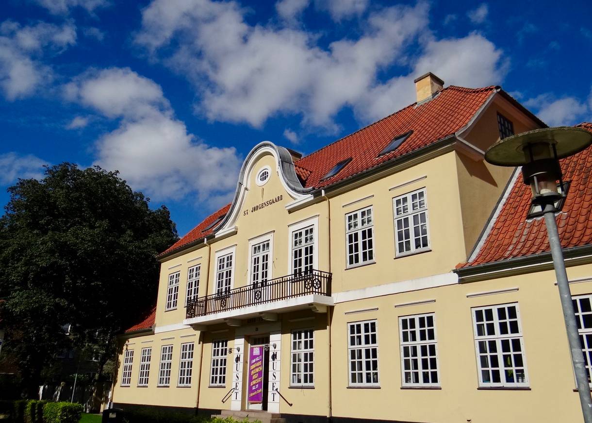 Gelbe Villa mit rotem Dach, am Eingang Werbung für eine Veranstaltung 