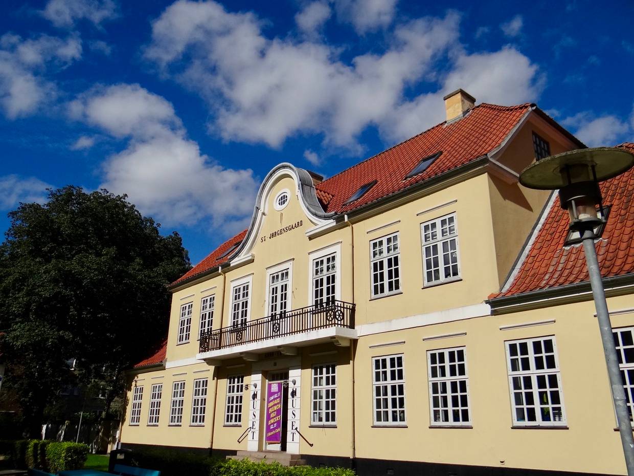 Gelbe Villa mit rotem Dach, am Eingang Werbung für eine Veranstaltung 