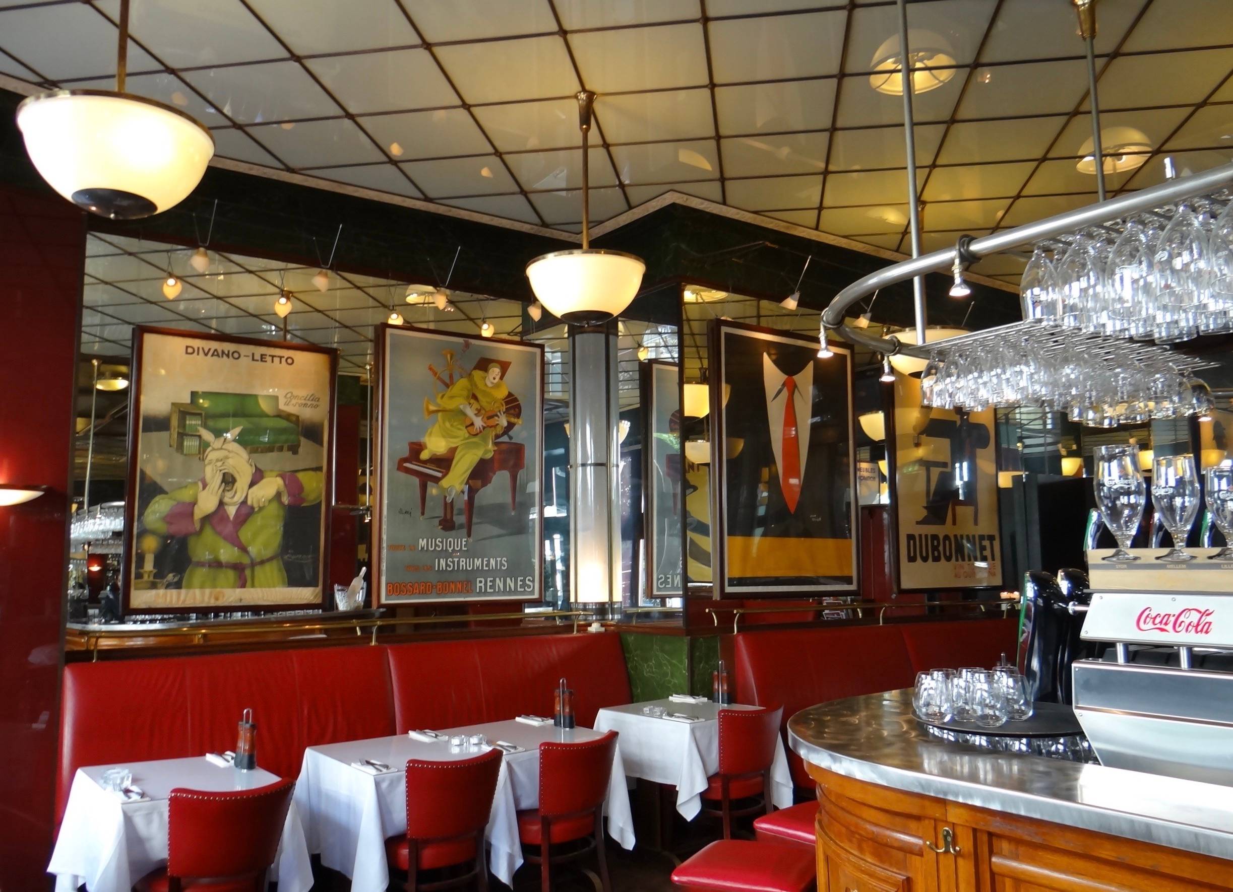 Restaurant mit roten Lederbänken, weißen Tischdecken und alten Werbeplakaten an den Wänden
