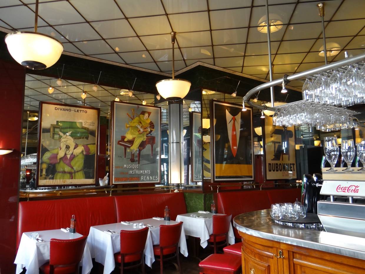 Restaurant mit roten Lederbänken, weißen Tischdecken und alten Werbeplakaten an den Wänden