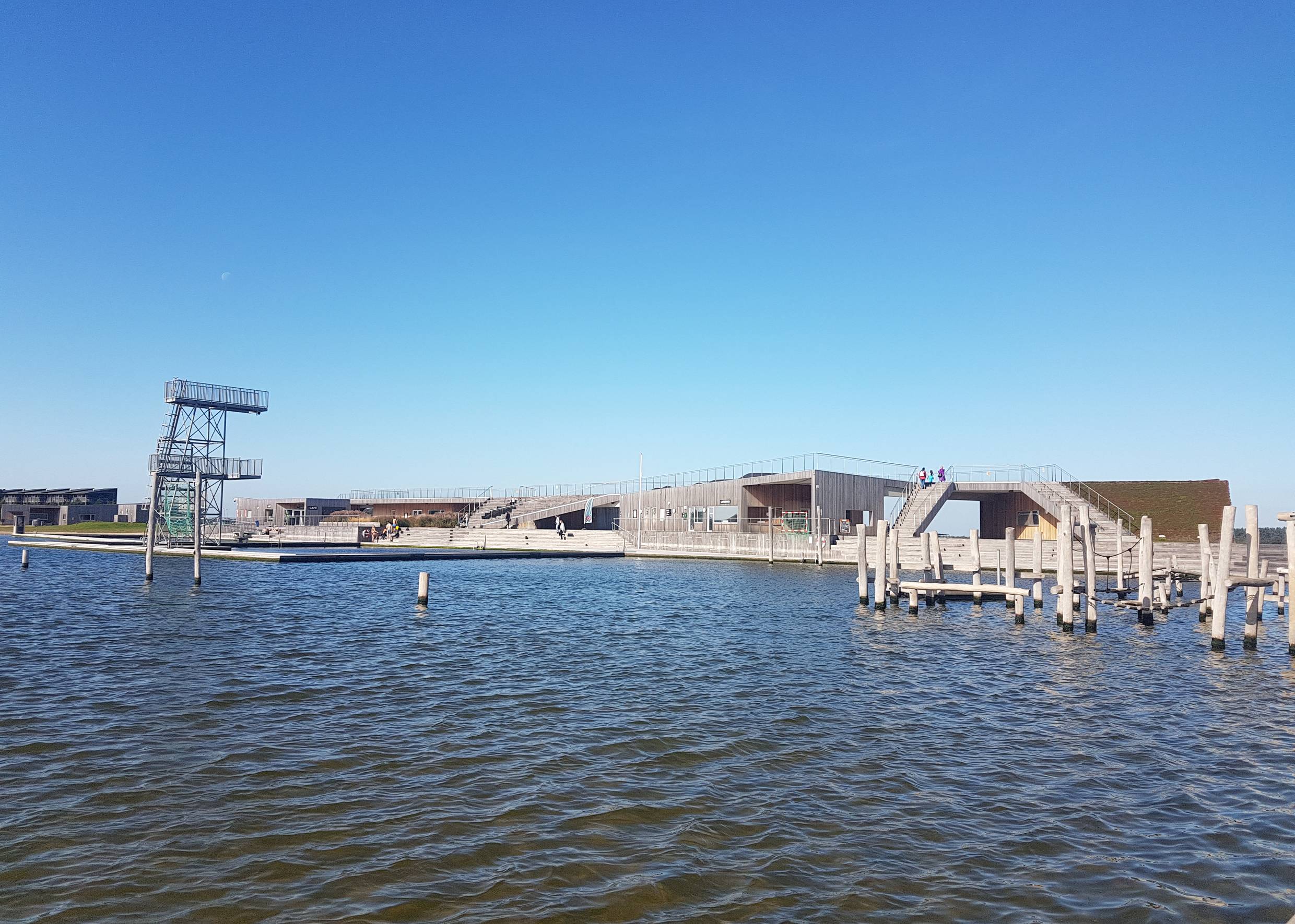 Holzgebäude mit Terrassen auf dem Dach, daneben ein Sprungturm