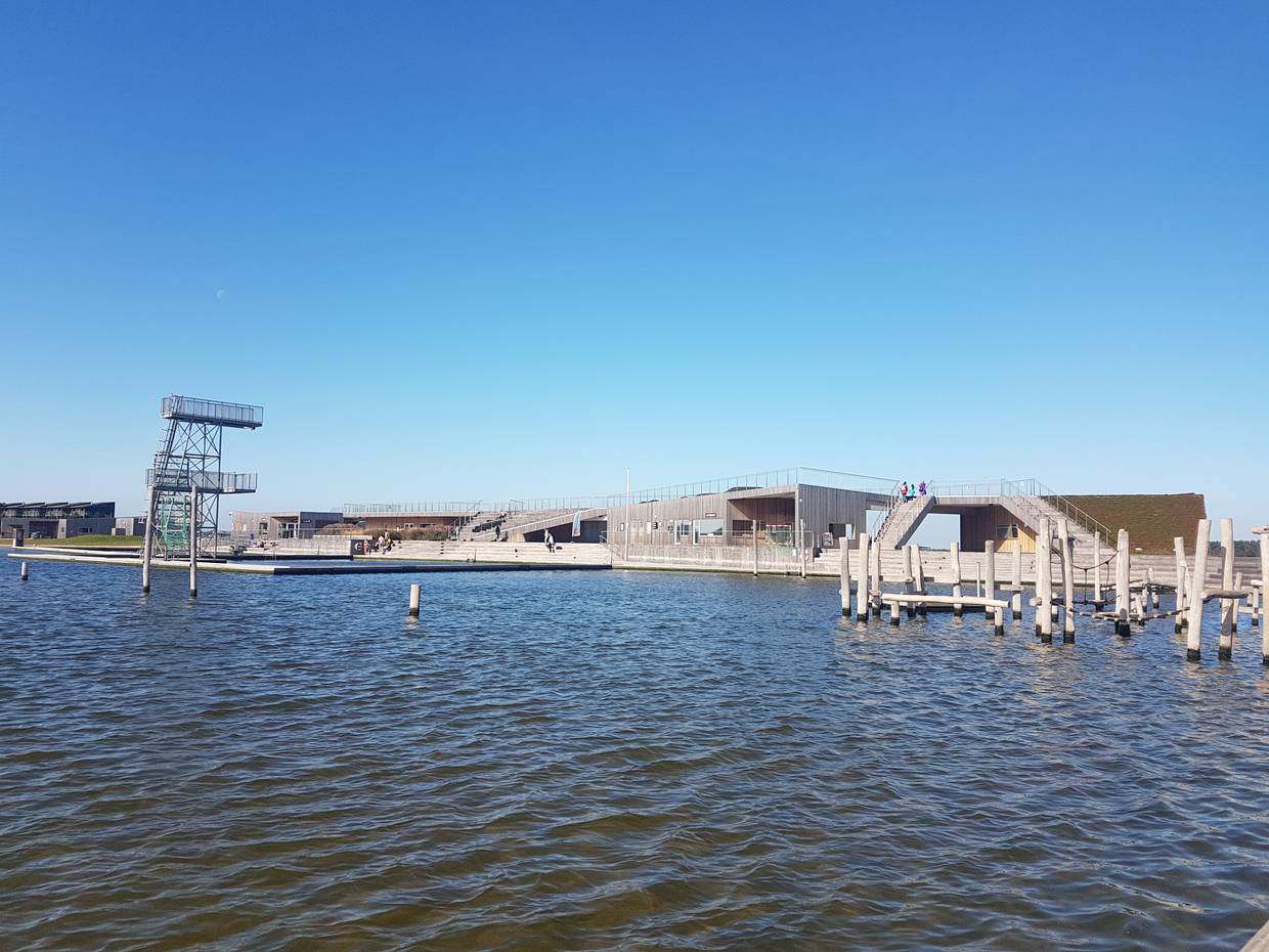 Holzgebäude mit Terrassen auf dem Dach, daneben ein Sprungturm