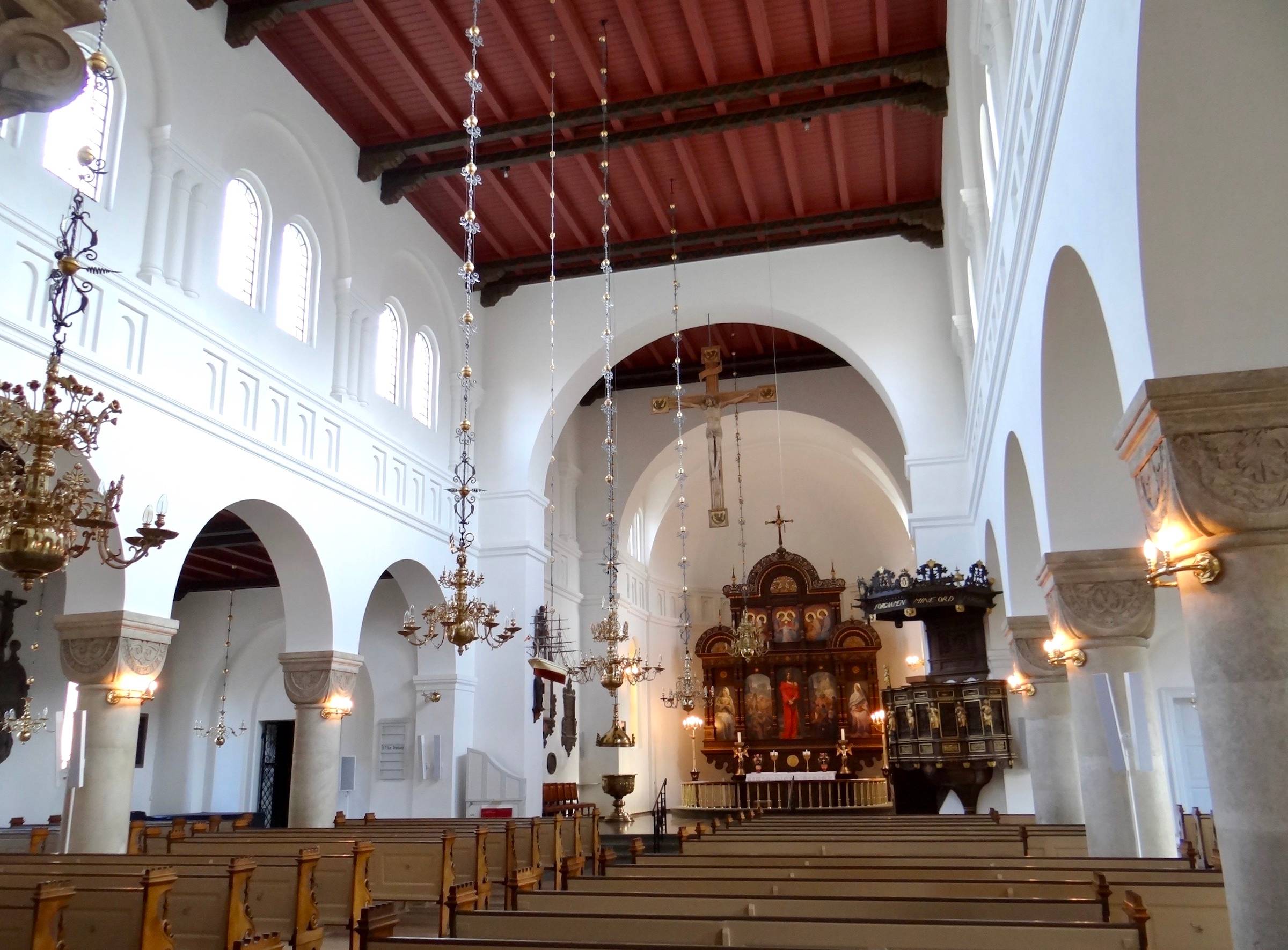 Innenraum einer Kirche mit weißem Gewölbe und filigranen Kronleuchtern