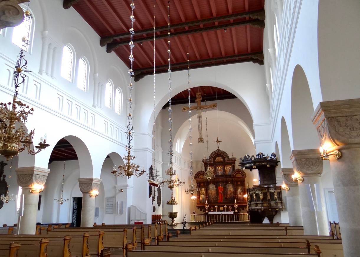 Innenraum einer Kirche mit weißem Gewölbe und filigranen Kronleuchtern