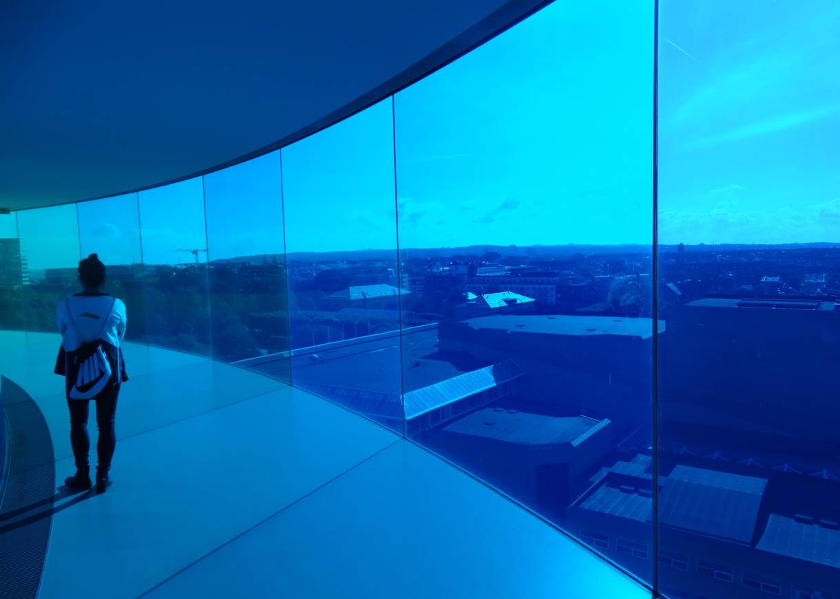 Blick auf die Stadt durch eine leuchtens blaue Glasfront