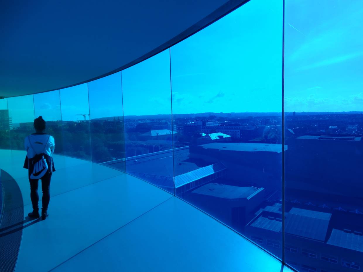 Blick auf die Stadt durch eine leuchtens blaue Glasfront