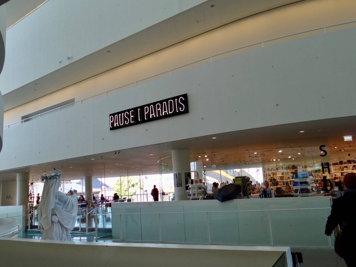 Blick ins Museumscafé, über dem Tresen steht mit Neonbuchstaben Pause im Paradies