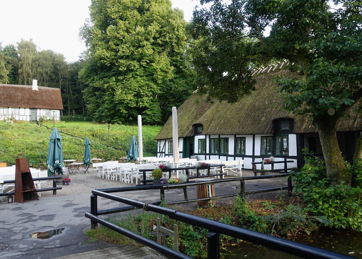 Fachwerkhaus mit einem Restaurant, davor weiße Gartenmöbel