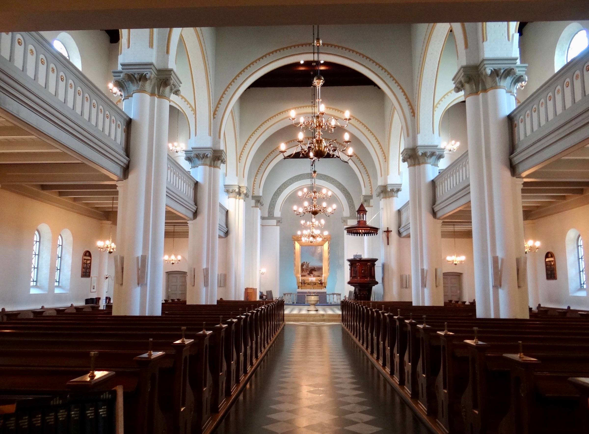 Inneraum einer weißen Kirche mit geschnitzten Holzbänken