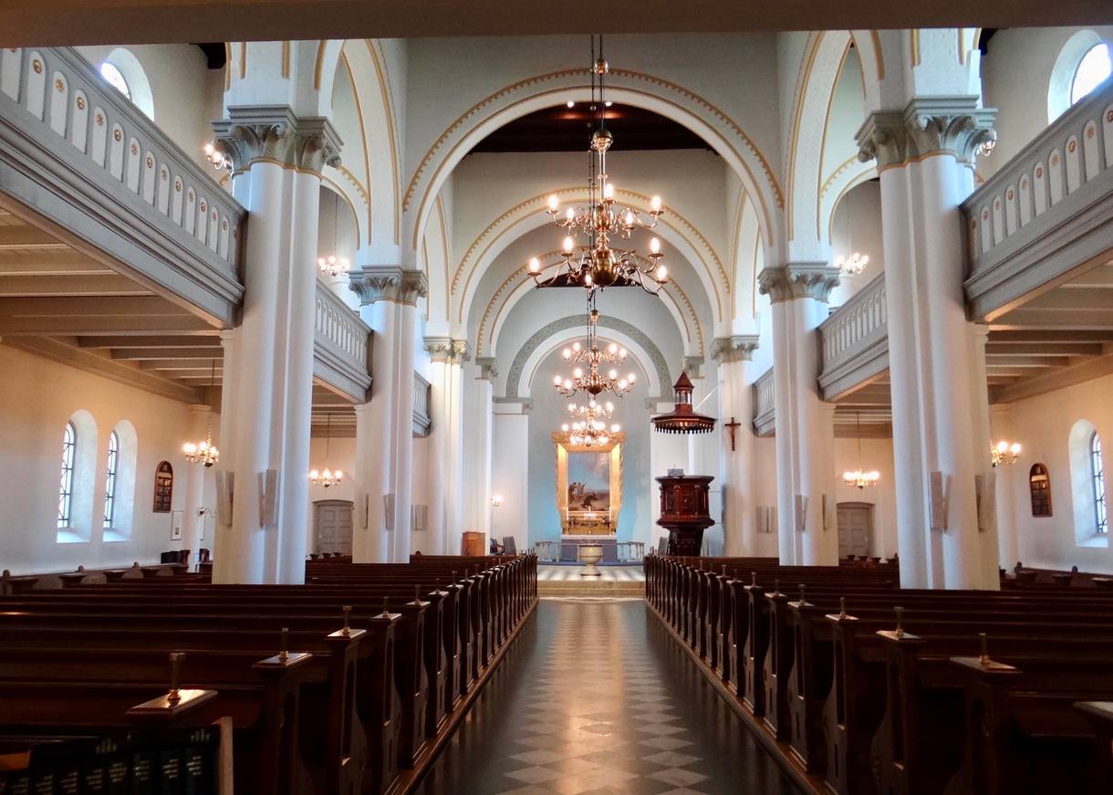 Inneraum einer weißen Kirche mit geschnitzten Holzbänken