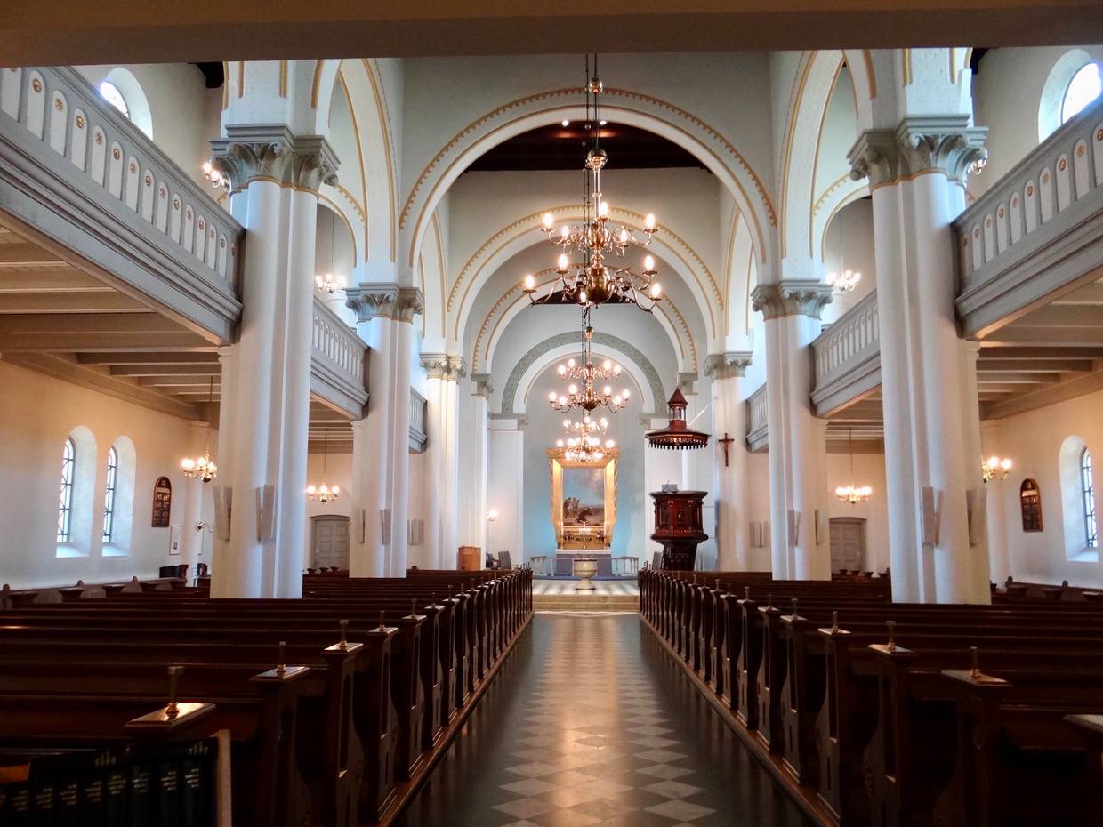 Inneraum einer weißen Kirche mit geschnitzten Holzbänken