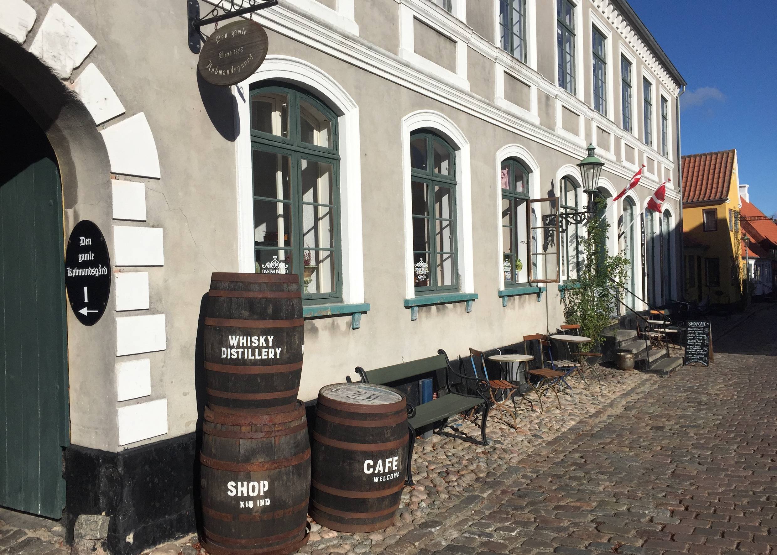 Alte Whisky-Fässer gestapelt vor dem grau-weißen Kaufmannshof