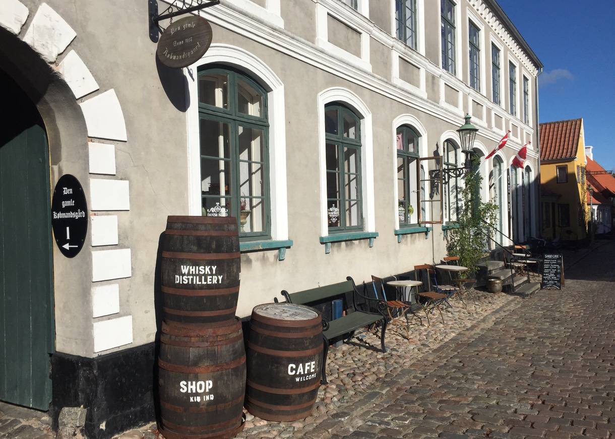 Alte Whisky-Fässer gestapelt vor dem grau-weißen Kaufmannshof