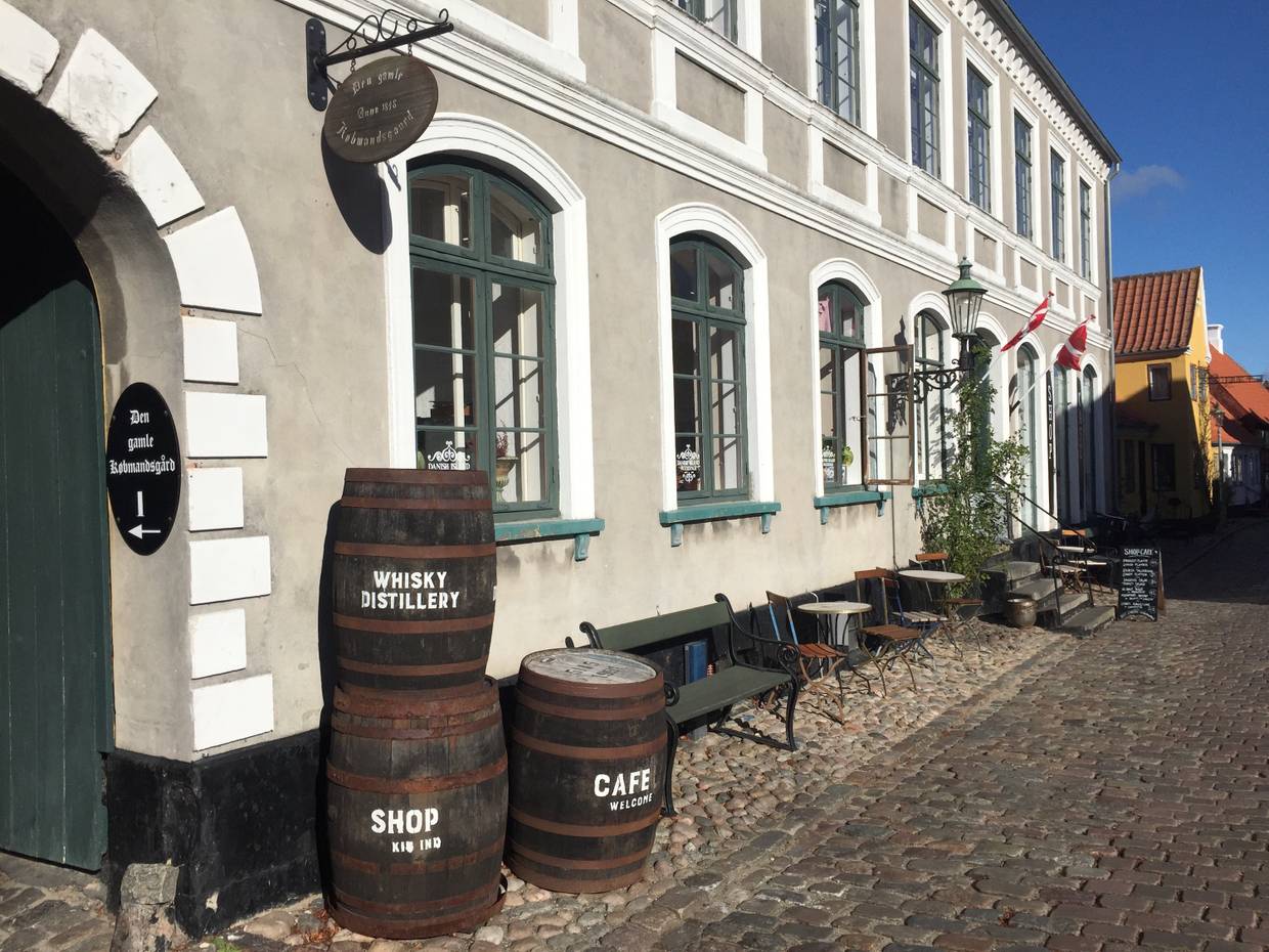 Alte Whisky-Fässer gestapelt vor dem grau-weißen Kaufmannshof