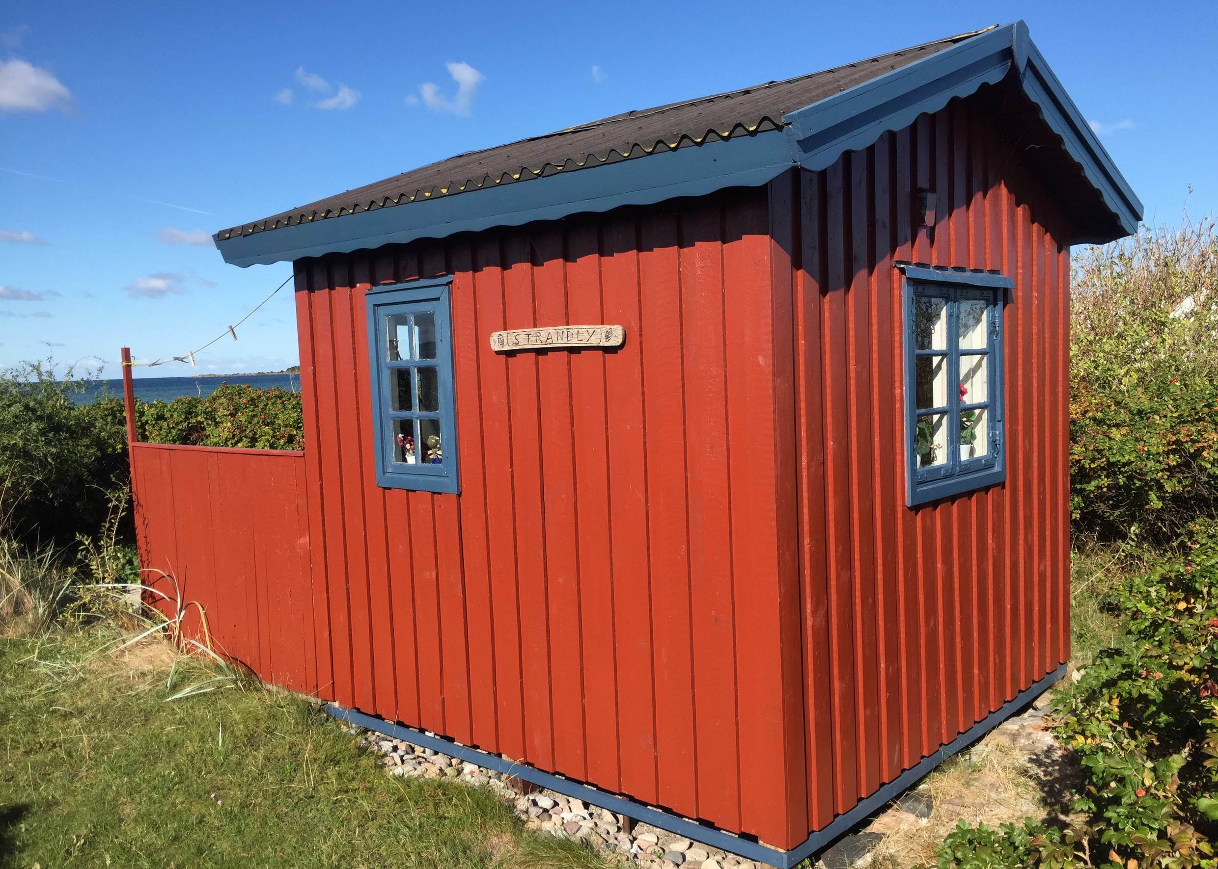 Rote kleine Holzhütte mit blauen Fensterrahmen