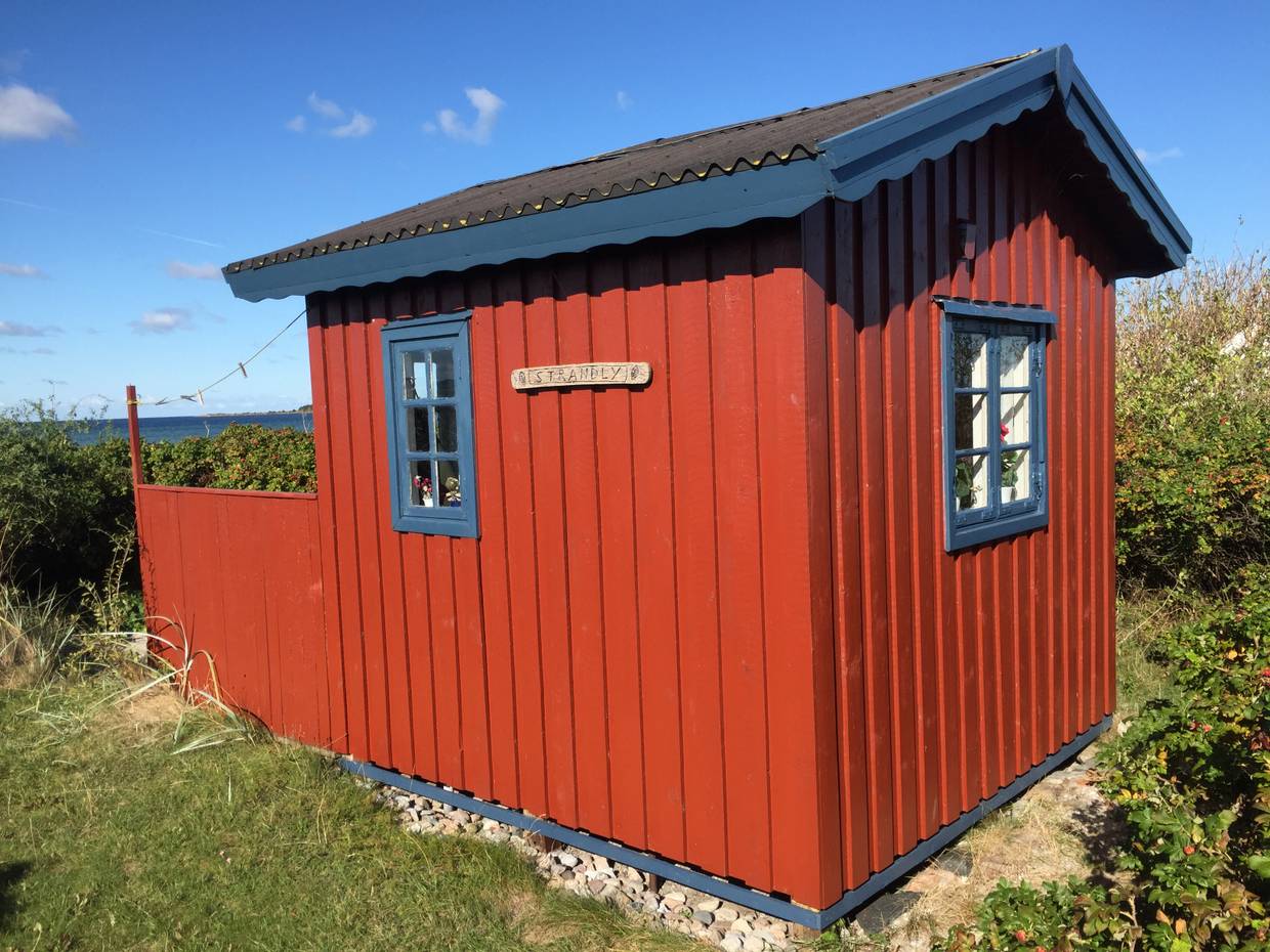 Rote kleine Holzhütte mit blauen Fensterrahmen