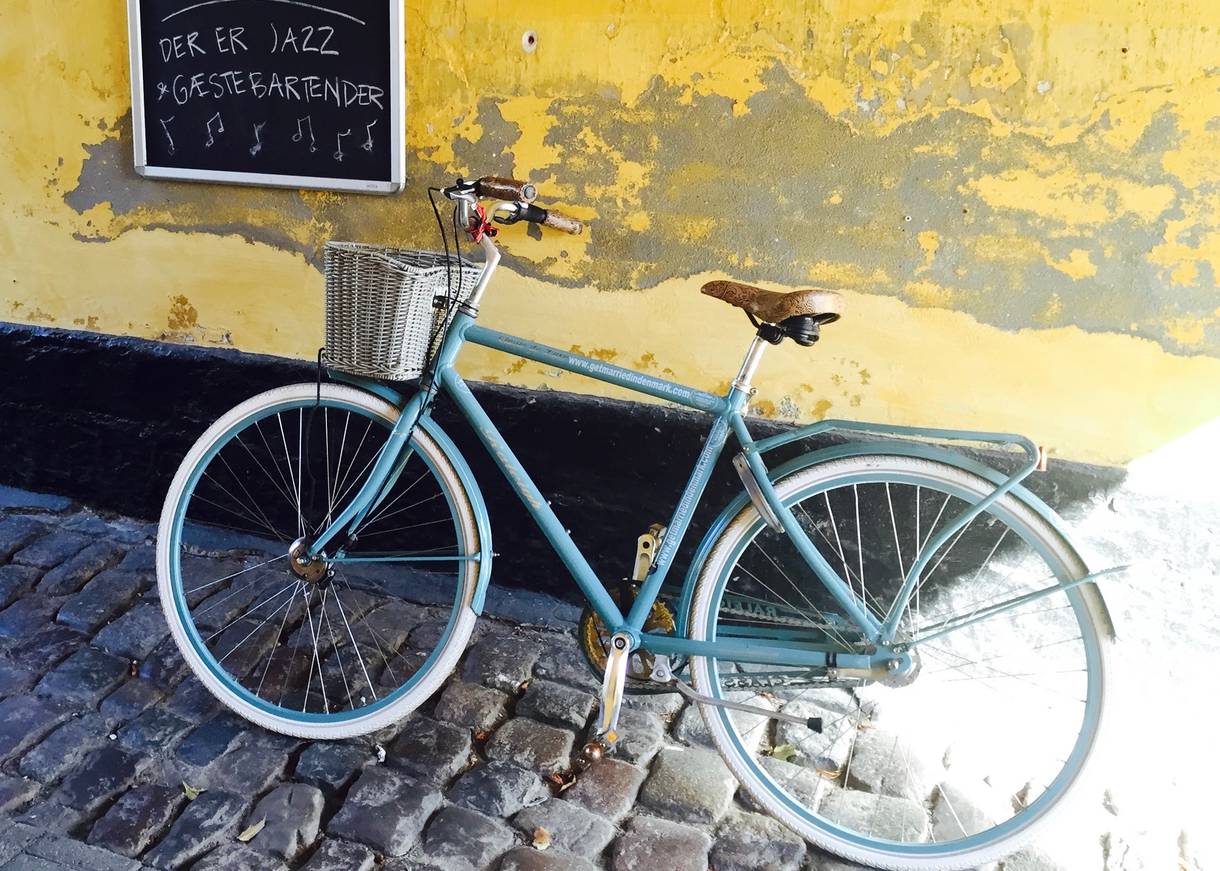 Altes blaues Fahrrad an gelber Wand mit Werbung für Hochzeit auf Ærø