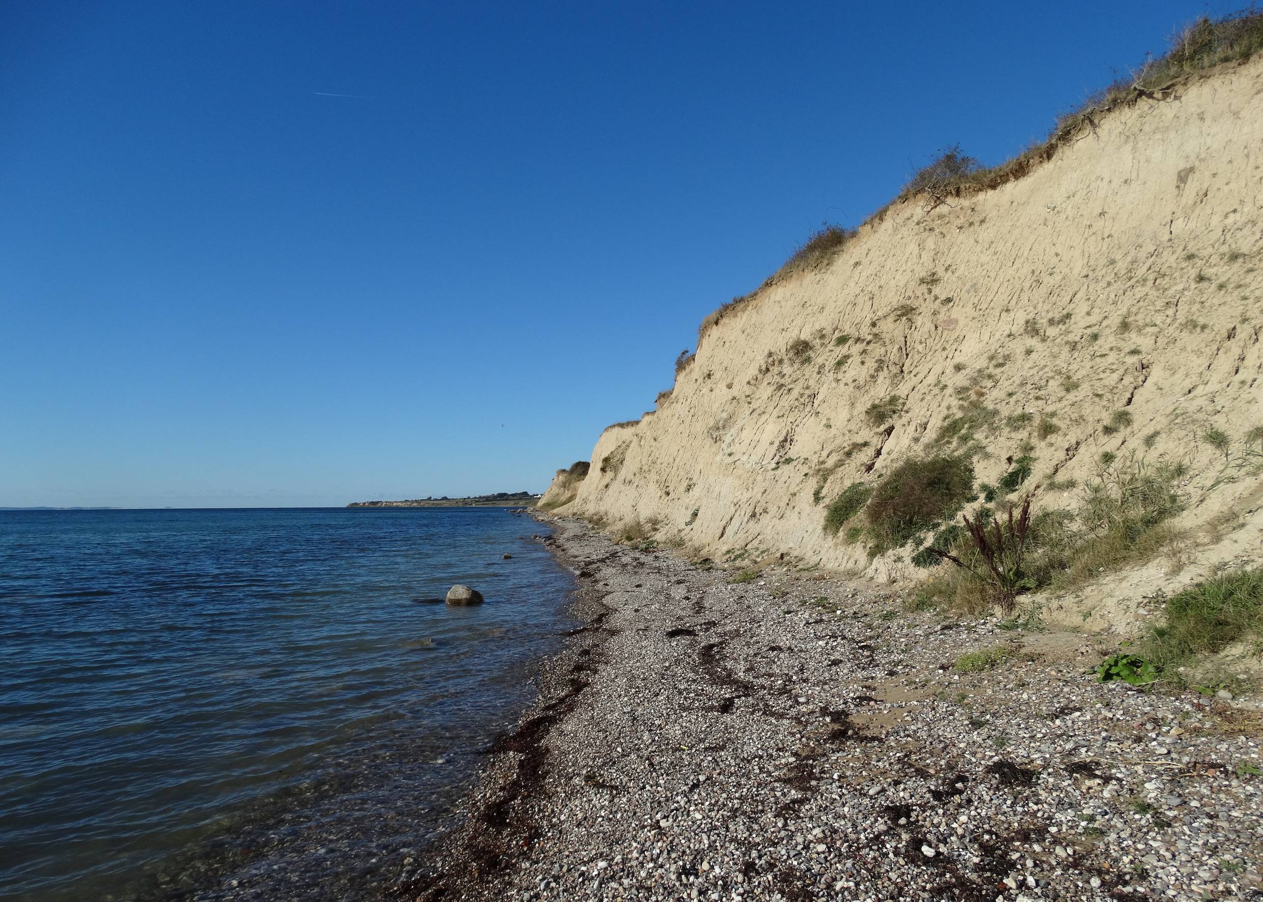 Sehr steiniger Strand unter einer sandigen Steilküste