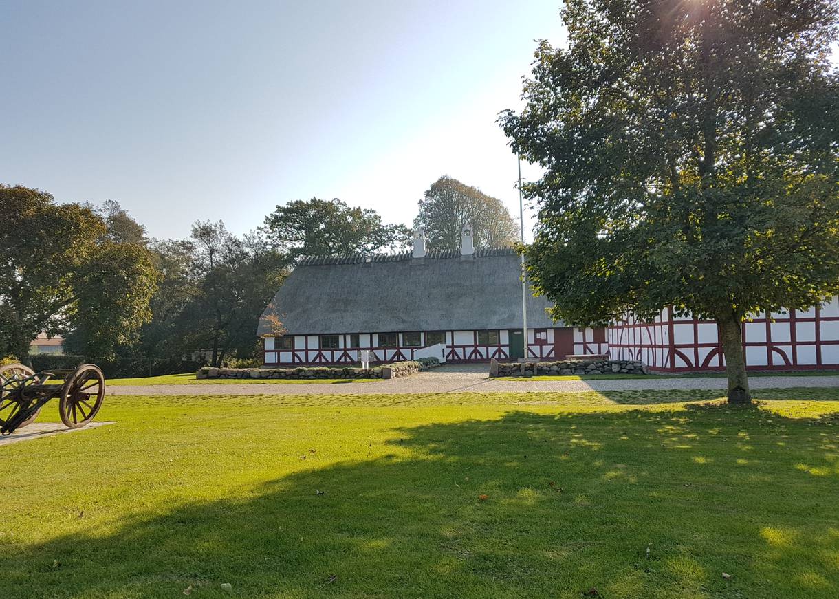 Ein langgezogener Fachwerkhof mit einer Wiese davor