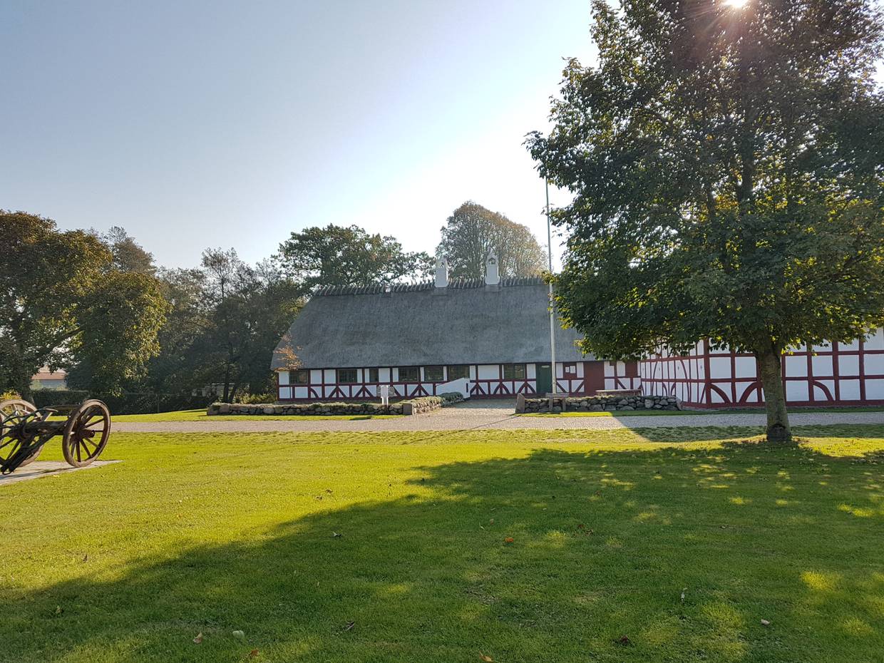 Ein langgezogener Fachwerkhof mit einer Wiese davor