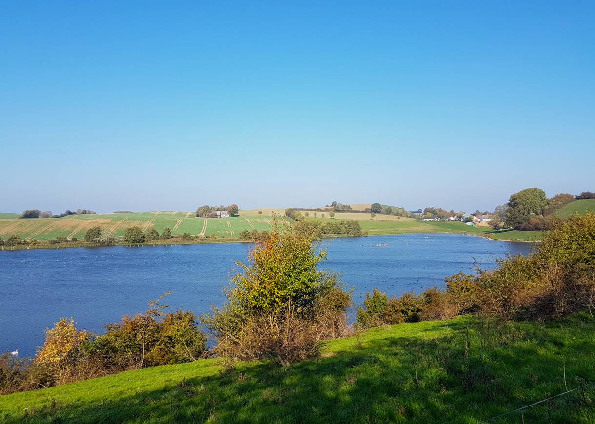 Blick auf einen See in einem grünen Tal