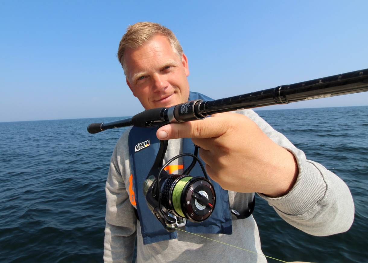 Angler zeigt eine Rute mit Stationärrlolle