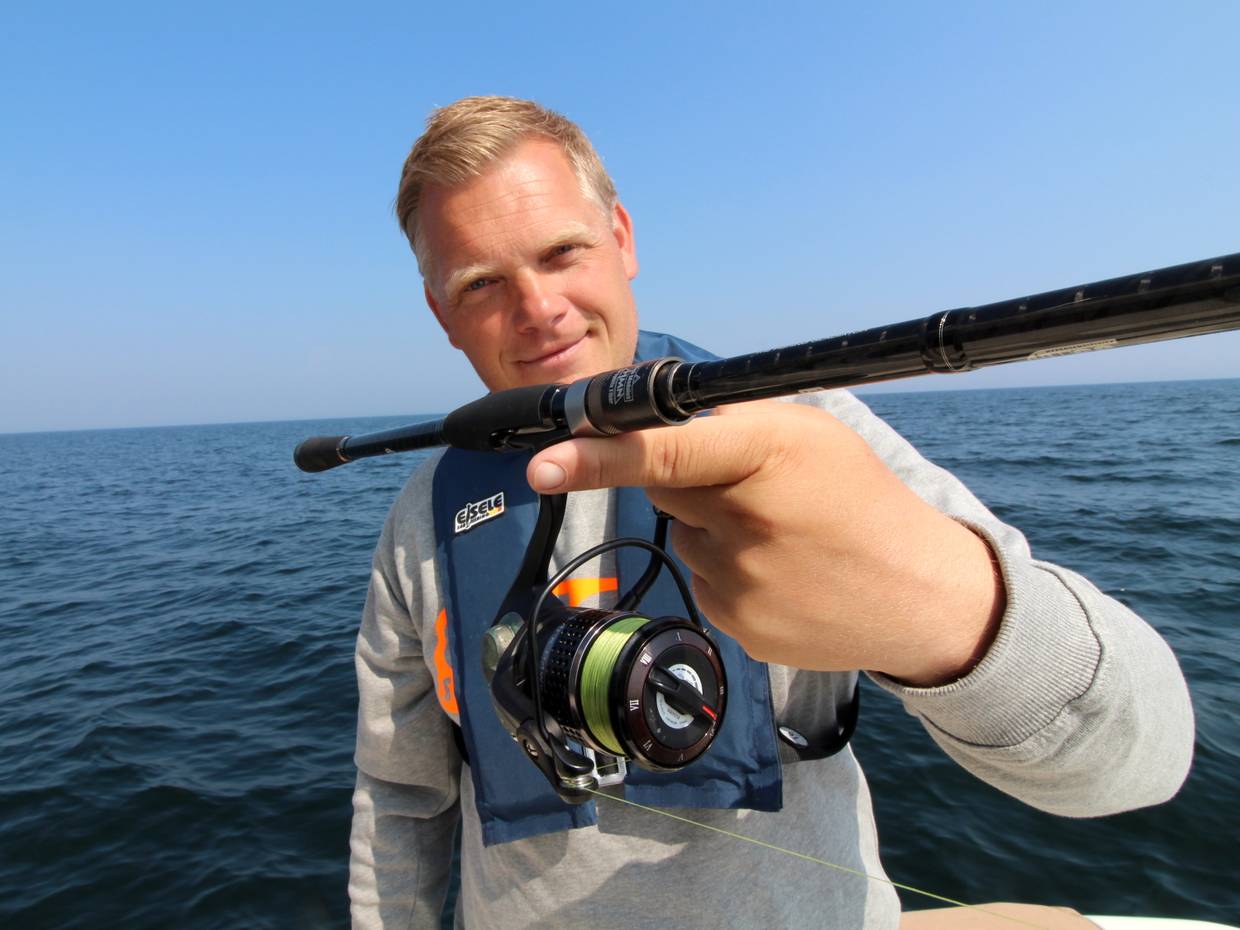 Angler zeigt eine Rute mit Stationärrlolle