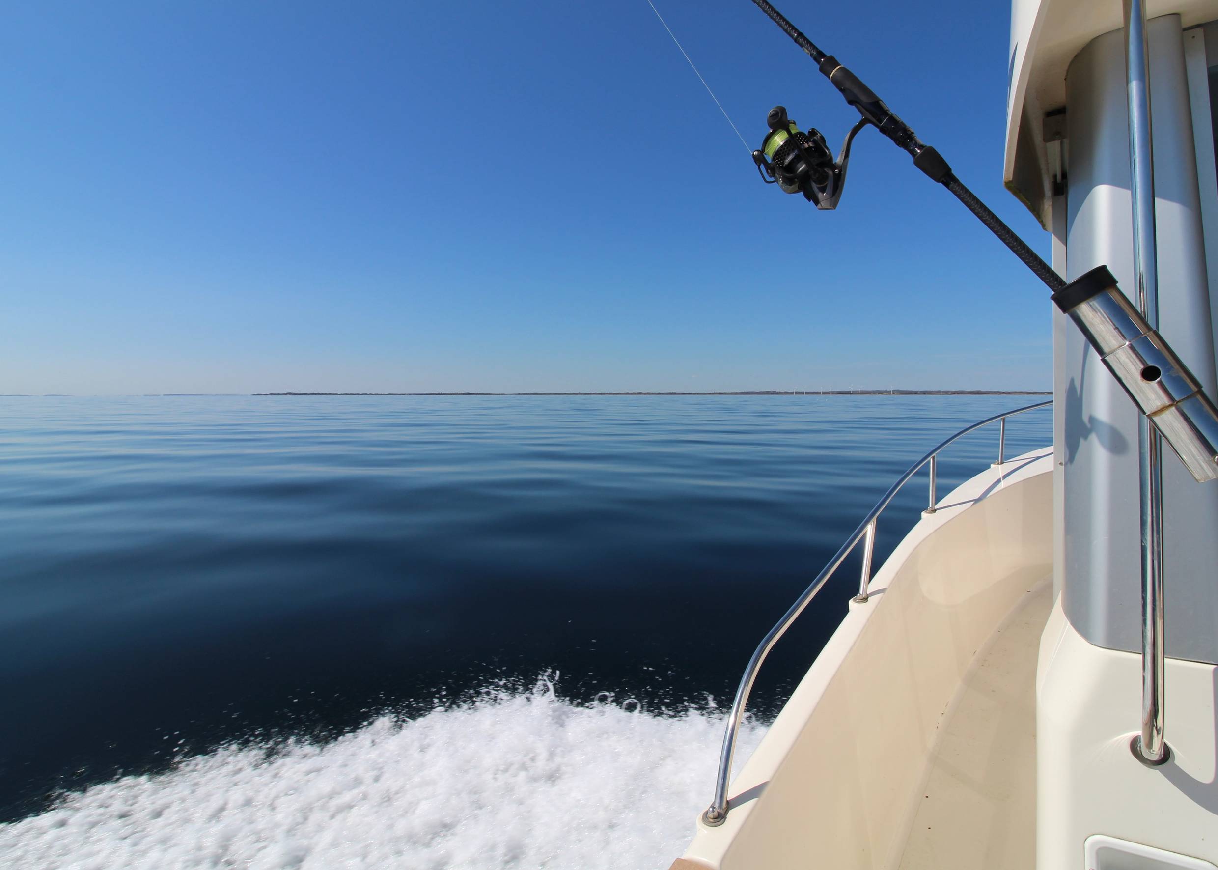 Blick auf ein windstilles Meer von einem Sportboot mit Angel aus