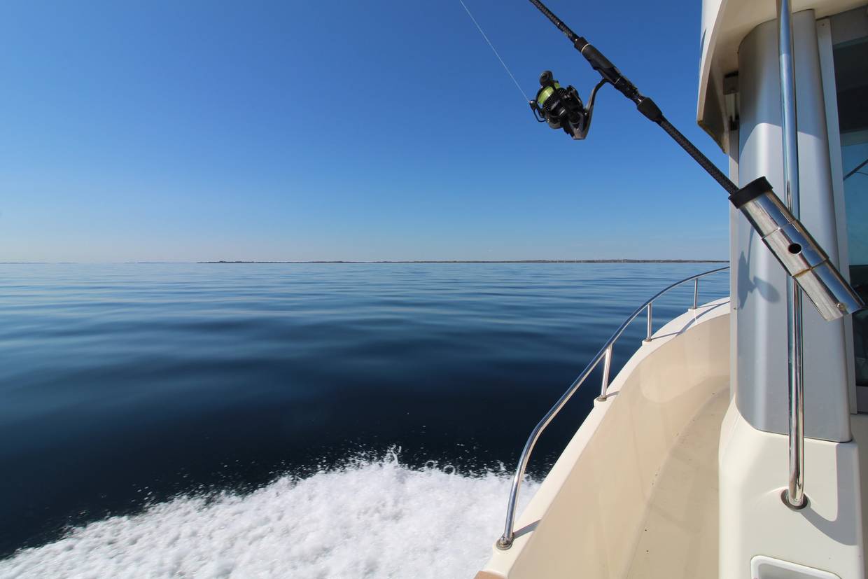 Blick auf ein windstilles Meer von einem Sportboot mit Angel aus