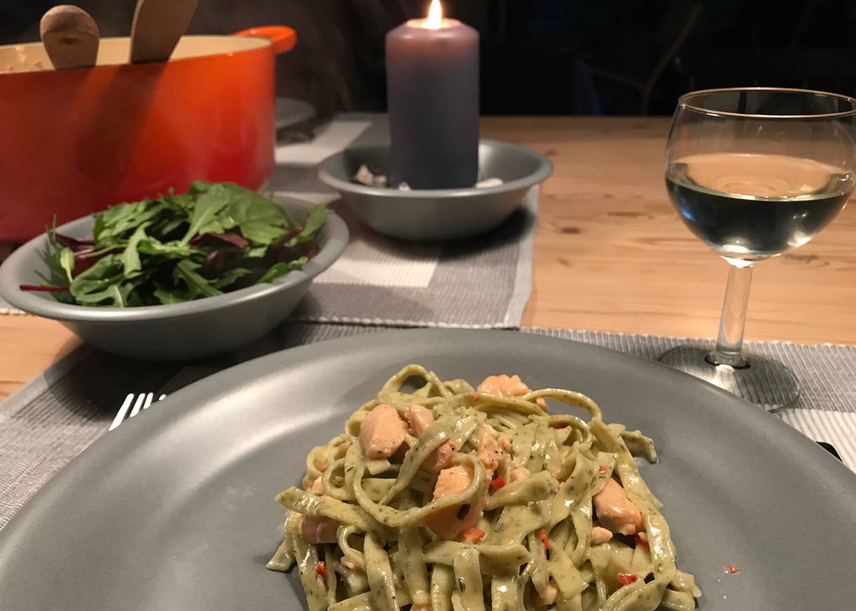 Ein gedeckter Tisch mit Bandnudeln, Salat, Wein und Kerzen