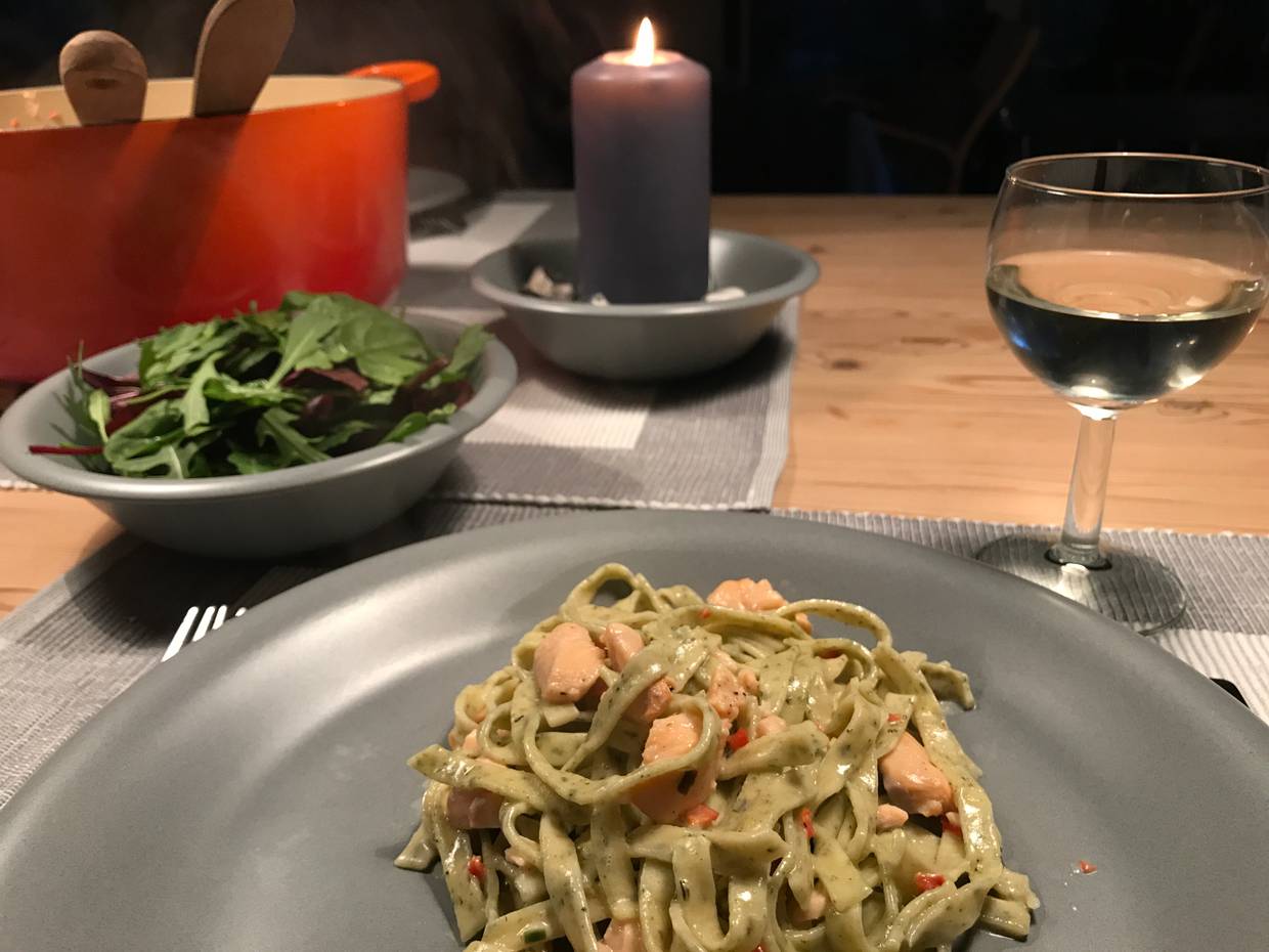 Ein gedeckter Tisch mit Bandnudeln, Salat, Wein und Kerzen
