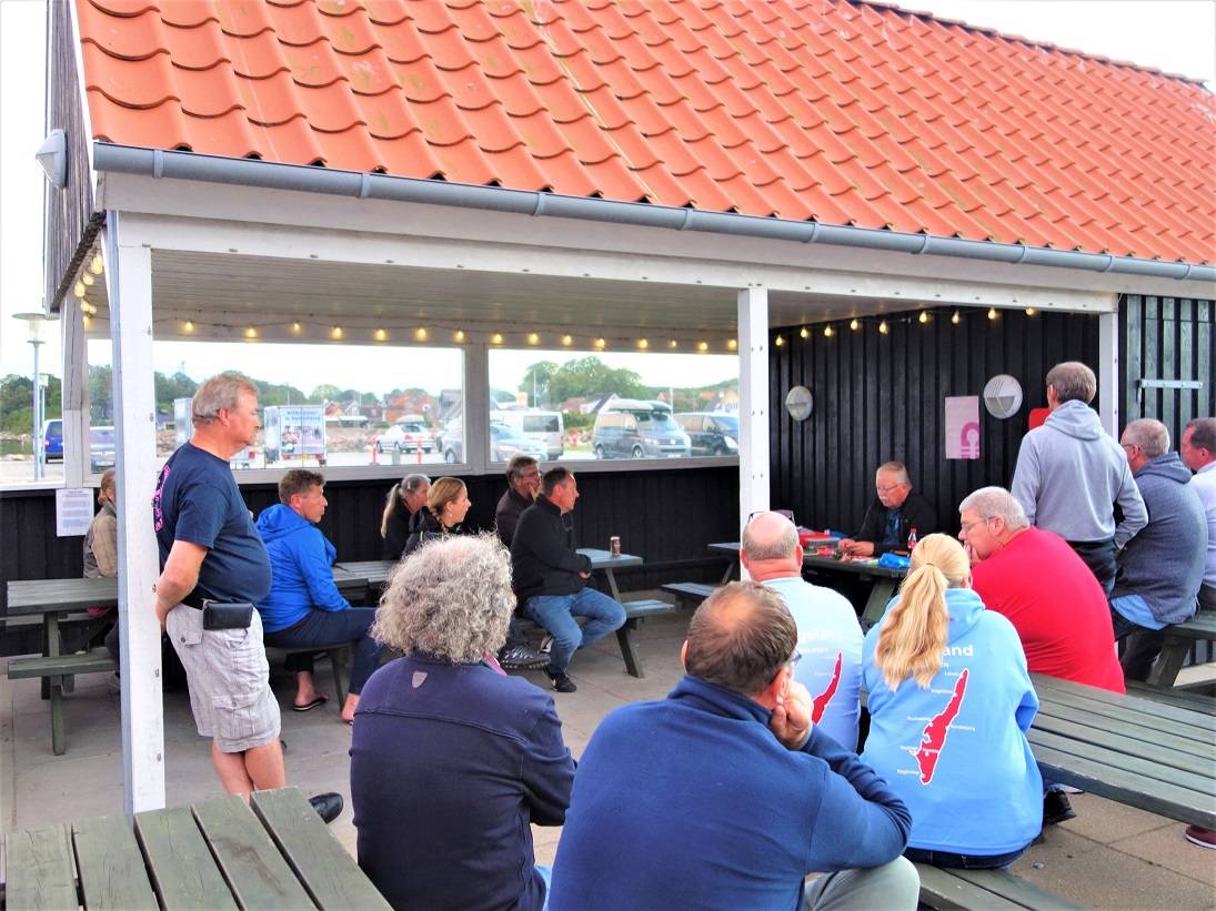 Zuhörer eines Angel-Vortrags auf einer überdachten Terrasse