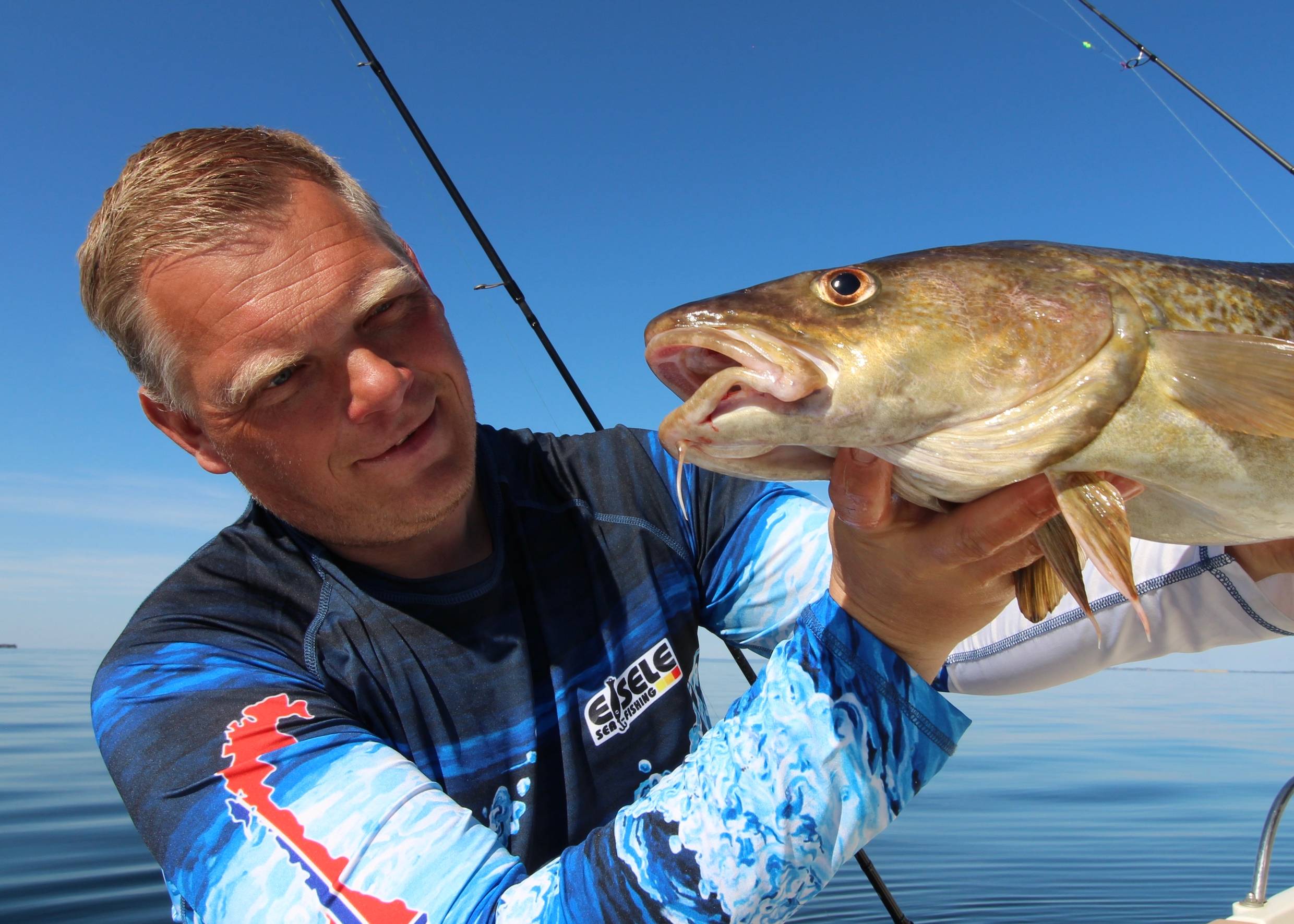 Angler zeigt einen recht großen, frisch gefangenen Dorch in die Kamera