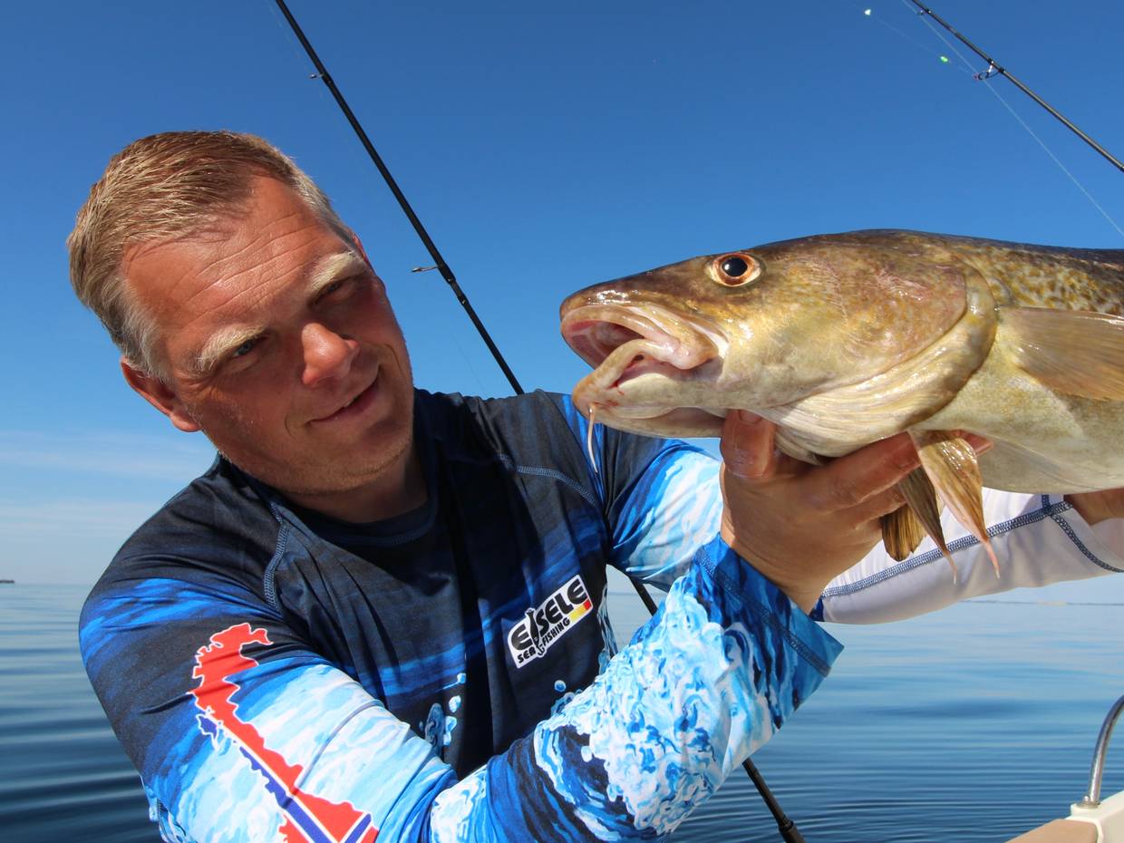 Angler zeigt einen recht großen, frisch gefangenen Dorch in die Kamera