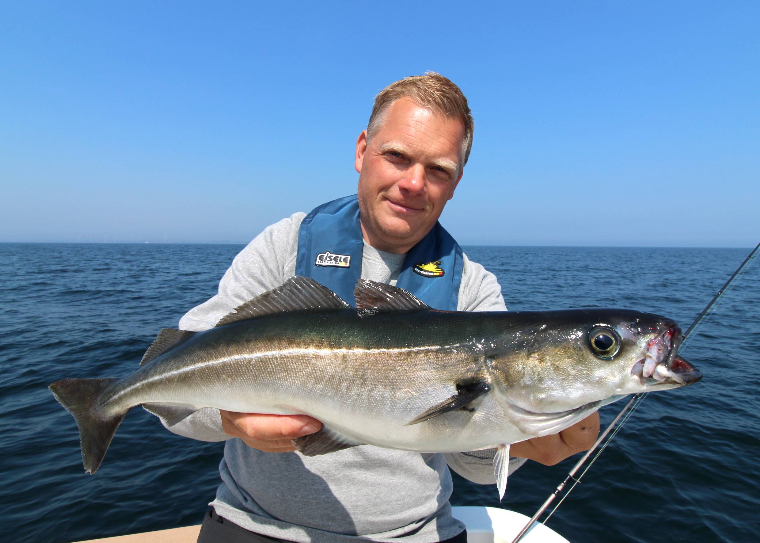 Angler mit einem frisch gefangenen Seelachs