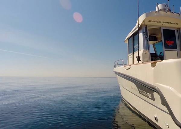 Weißes Sportboot in der Morgensonne auf der windstillen See