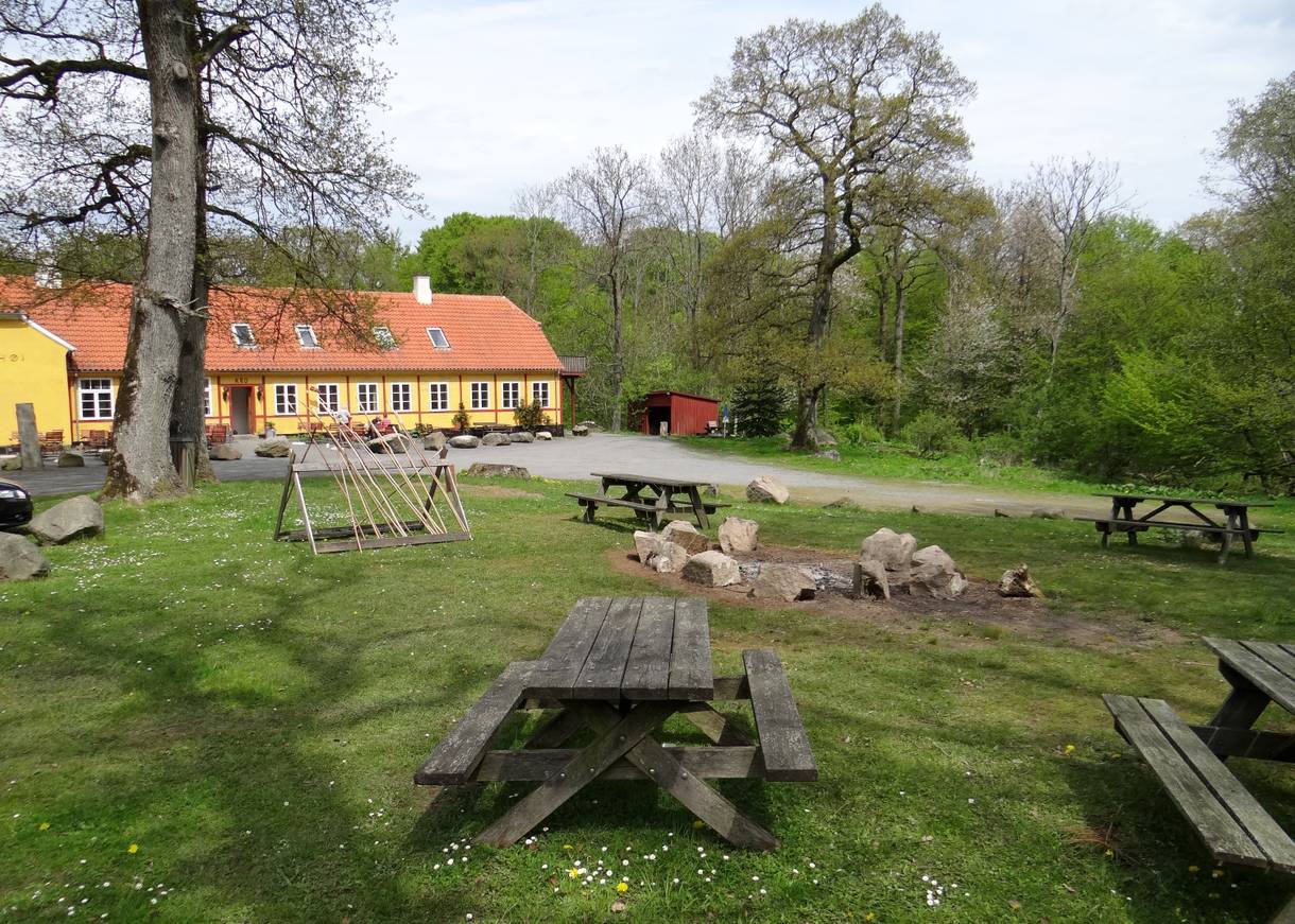 Picknickplatz mit Feuerstelle vor einem gelben Hof