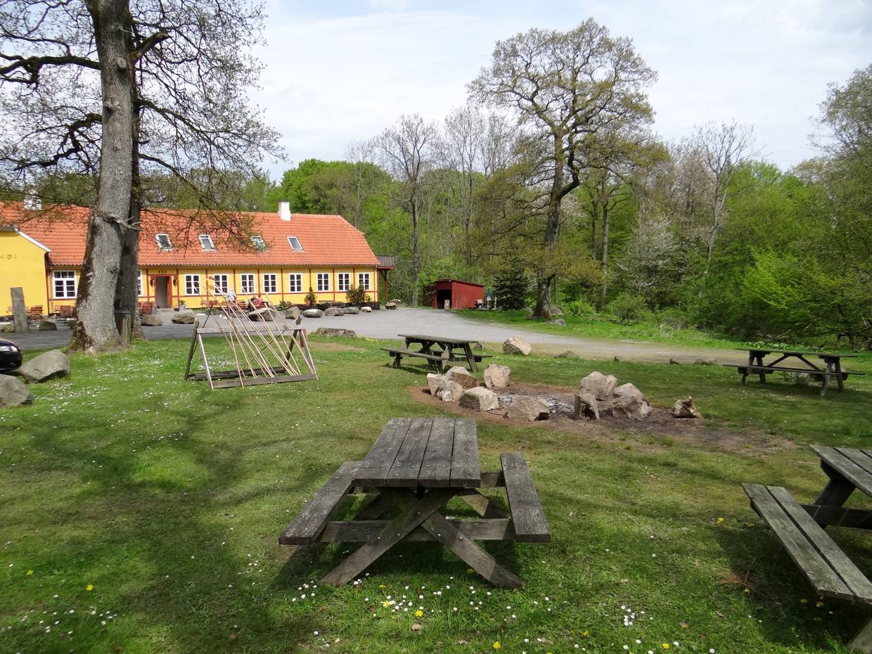 Picknickplatz mit Feuerstelle vor einem gelben Hof