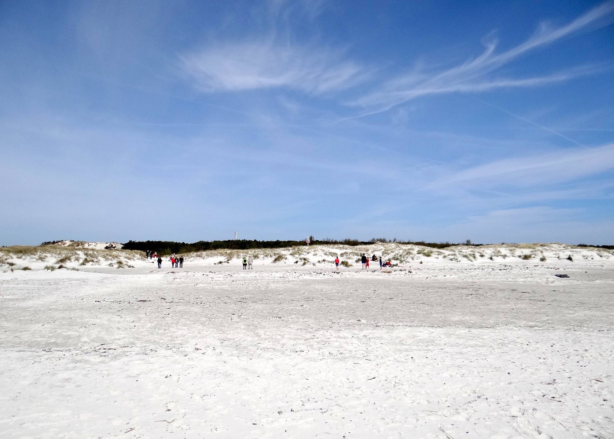 Weißer Strand auf Bornholm, im Hintergrund Spaziergänger vor den Dünen