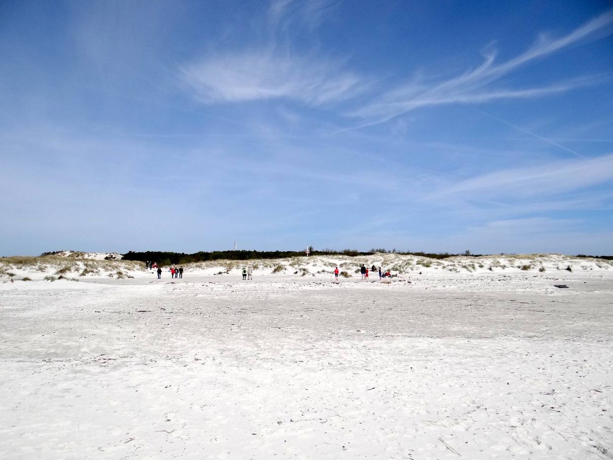 Weißer Strand auf Bornholm, im Hintergrund Spaziergänger vor den Dünen